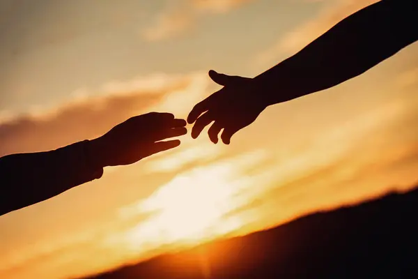 Two hands holding each other during a sunset